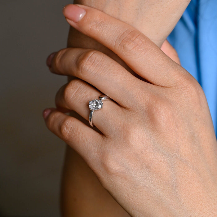 Oval moissanite open shank solitaire engagement ring with the stone tilted in four ball tipped claws on a sweeping polished white gold band, view 2