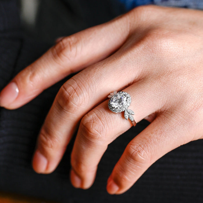 Oval moissanite halo engagement ring with a pave halo and pave set leaves on each shoulder of a white gold band, view 2