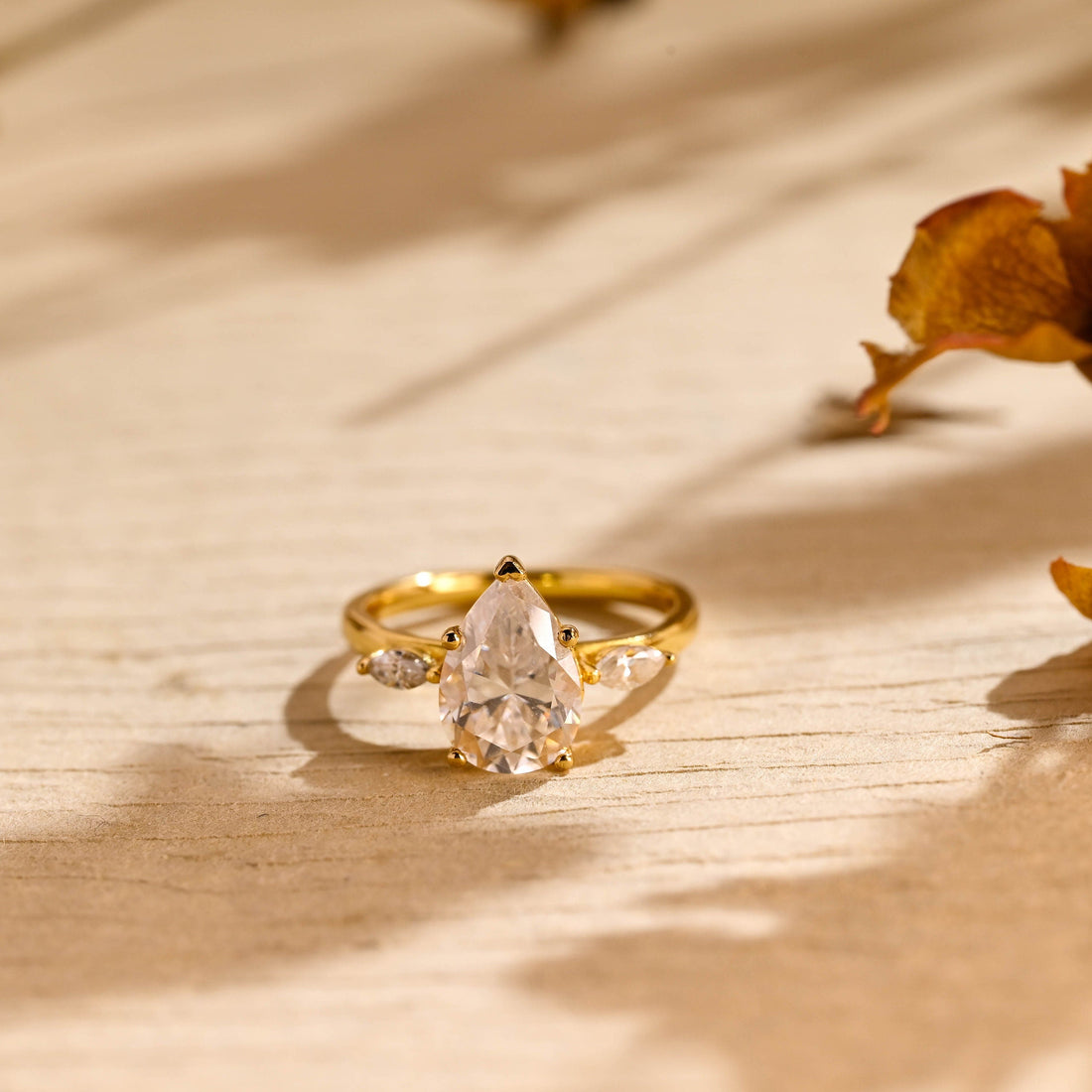 Pear cut moissanite three stone engagement ring with two marquise side stones on a smooth tapered yellow gold band