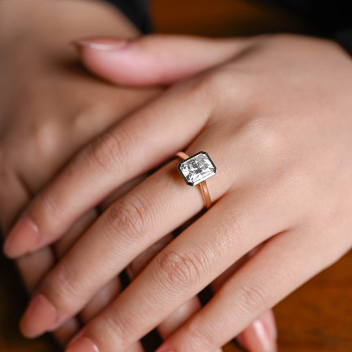 Radiant cut moissanite bezel set solitaire engagement ring with a white gold bezel on a tapered yellow gold cathedral band, view 2