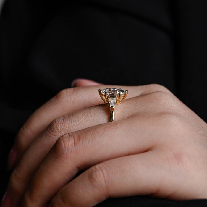 Marquise cut moissanite three stone engagement ring with tapered baguette side stones on a plain yellow gold band, view 2
