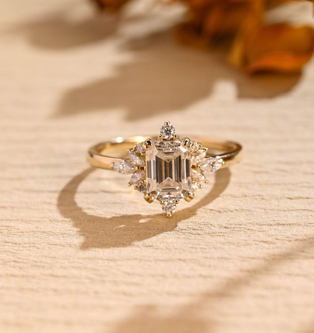 Emerald cut moissanite wreath cluster engagement ring with a fan of marquise stones on each side and round stones at the top and bottom in yellow gold
