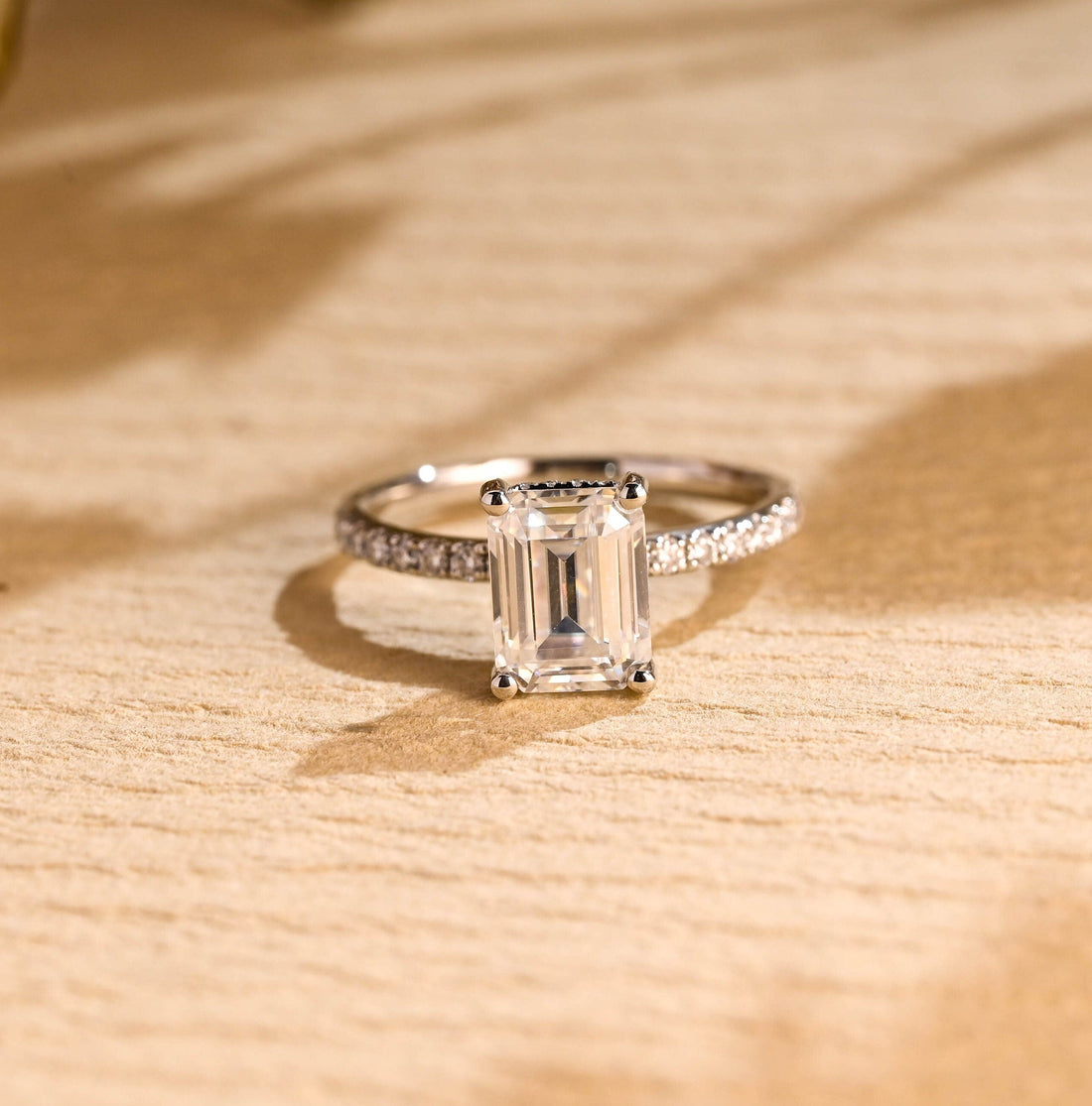 Emerald cut moissanite hidden halo engagement ring with four claws and a pave set white gold band