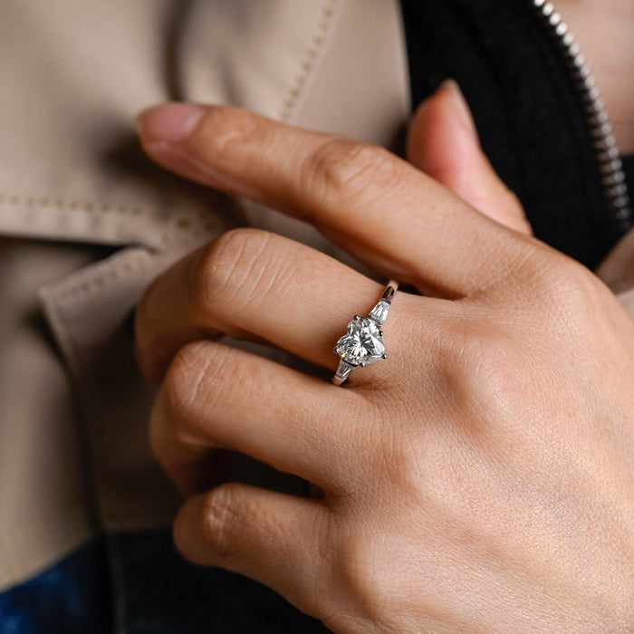 Heart cut moissanite three stone engagement ring with tapered baguette side stones on a white gold band, view 2