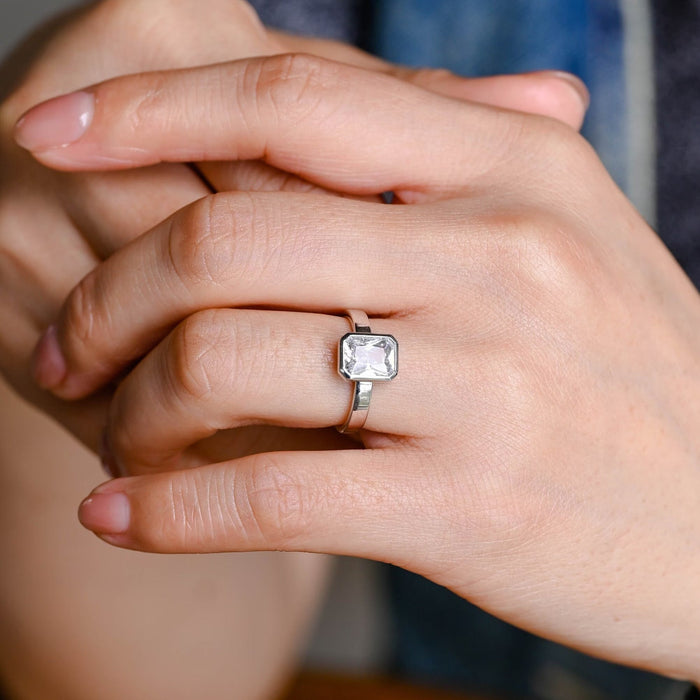 Radiant cut moissanite bezel set solitaire engagement ring on a wide flat polished white gold band, view 2