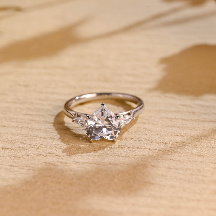 Heart cut moissanite three stone engagement ring with pear cut side stones on a polished white gold band