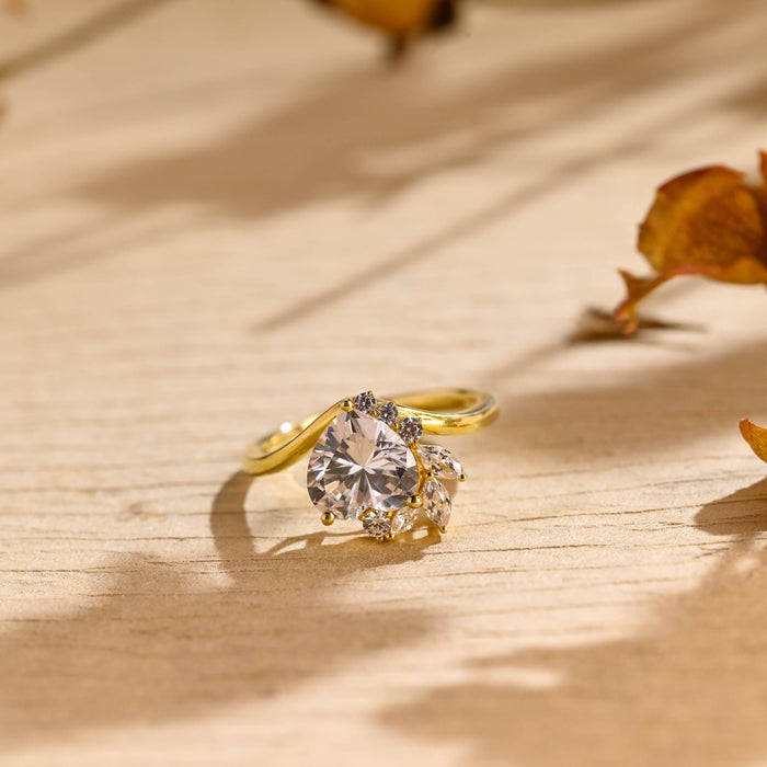 Heart cut moissanite cluster engagement ring with marquise leaf side stones on a yellow gold bypass band