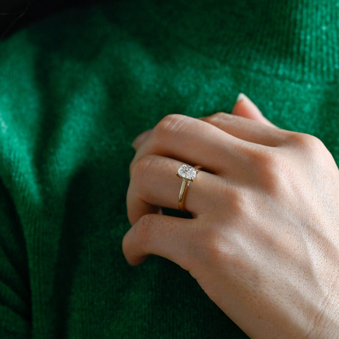 Elongated cushion moissanite hidden halo engagement ring in four claws on a smooth tapered yellow gold band, view 2