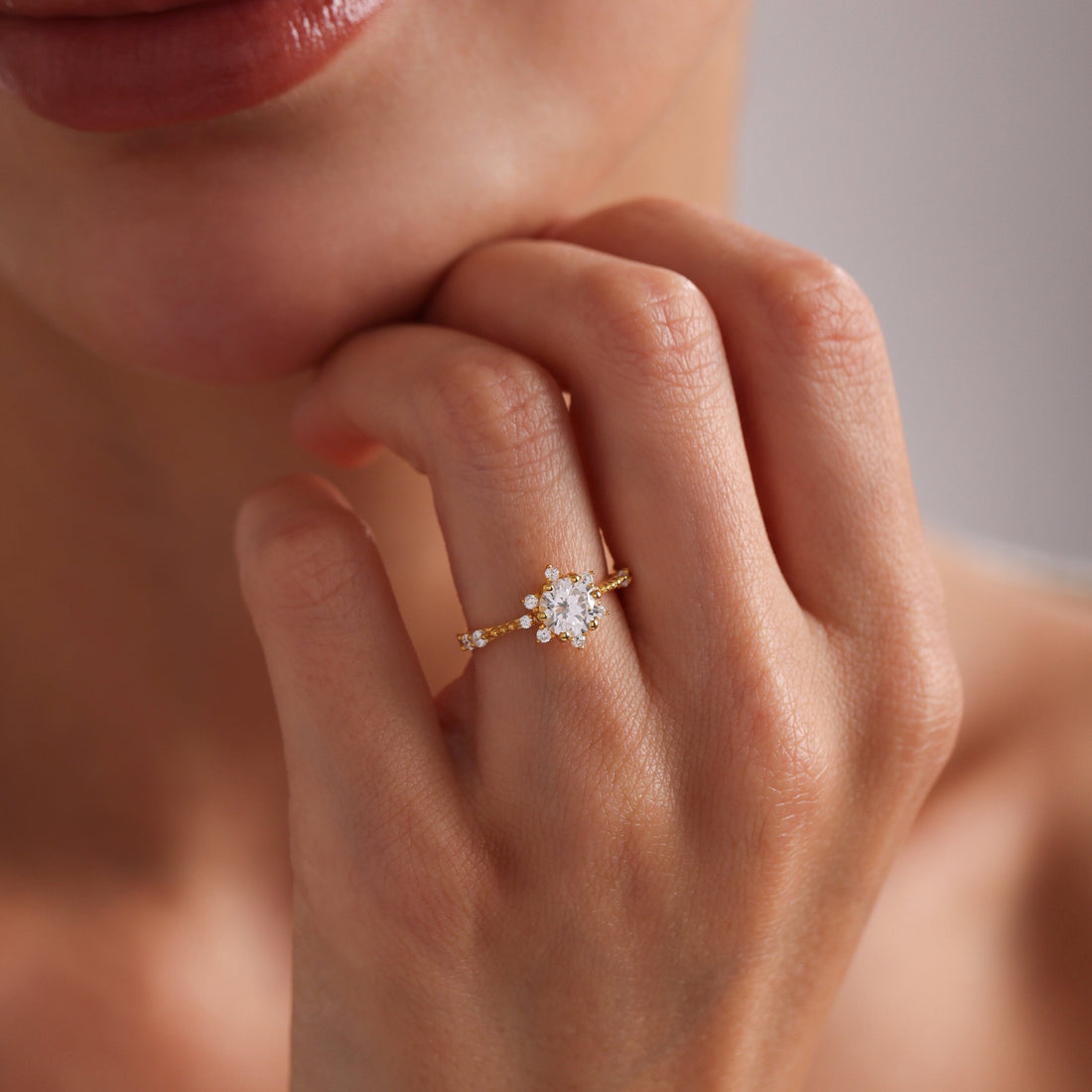 Round cut moissanite snowflake cluster engagement ring with small round stones on a beaded gold band