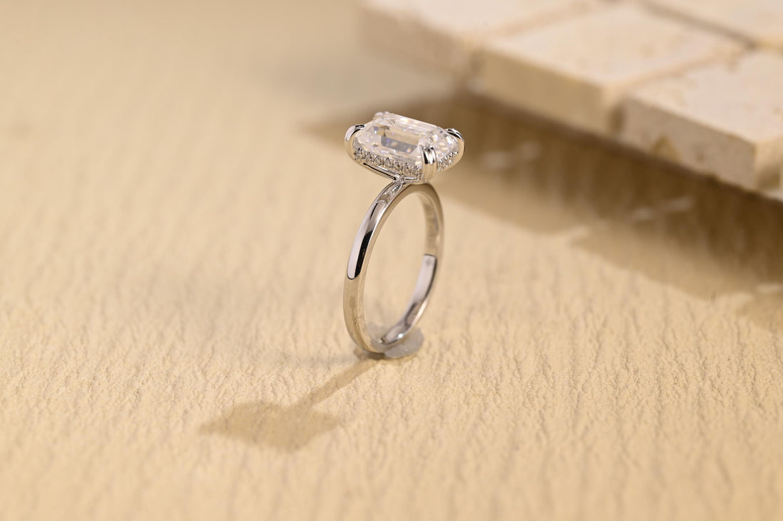 Emerald cut moissanite hidden halo engagement ring in four double claws with tiny stones under the stone on a plain polished white gold band