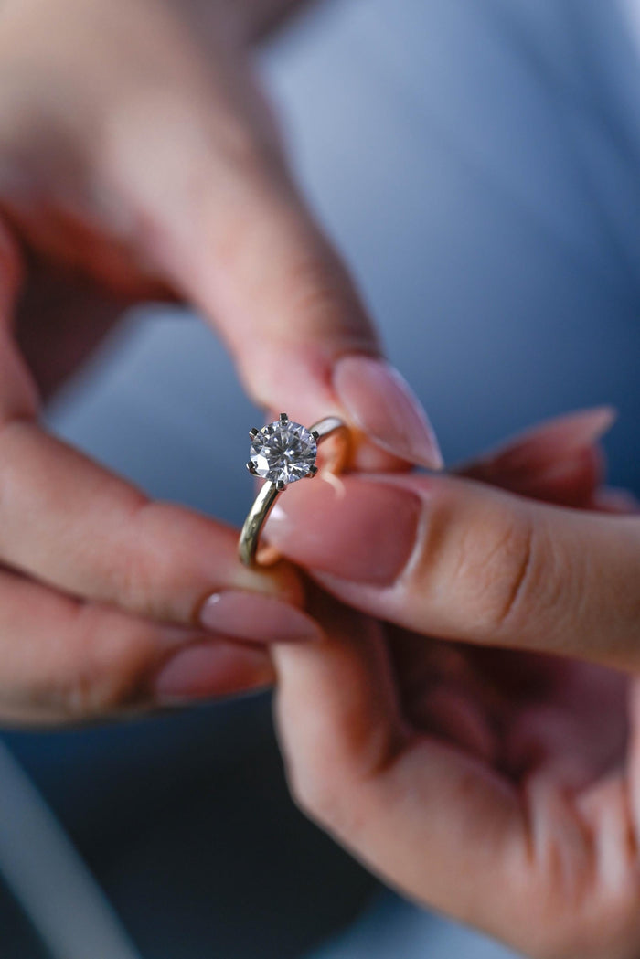 Round moissanite classic solitaire engagement ring in six slim claws on a plain polished yellow gold band, view 2