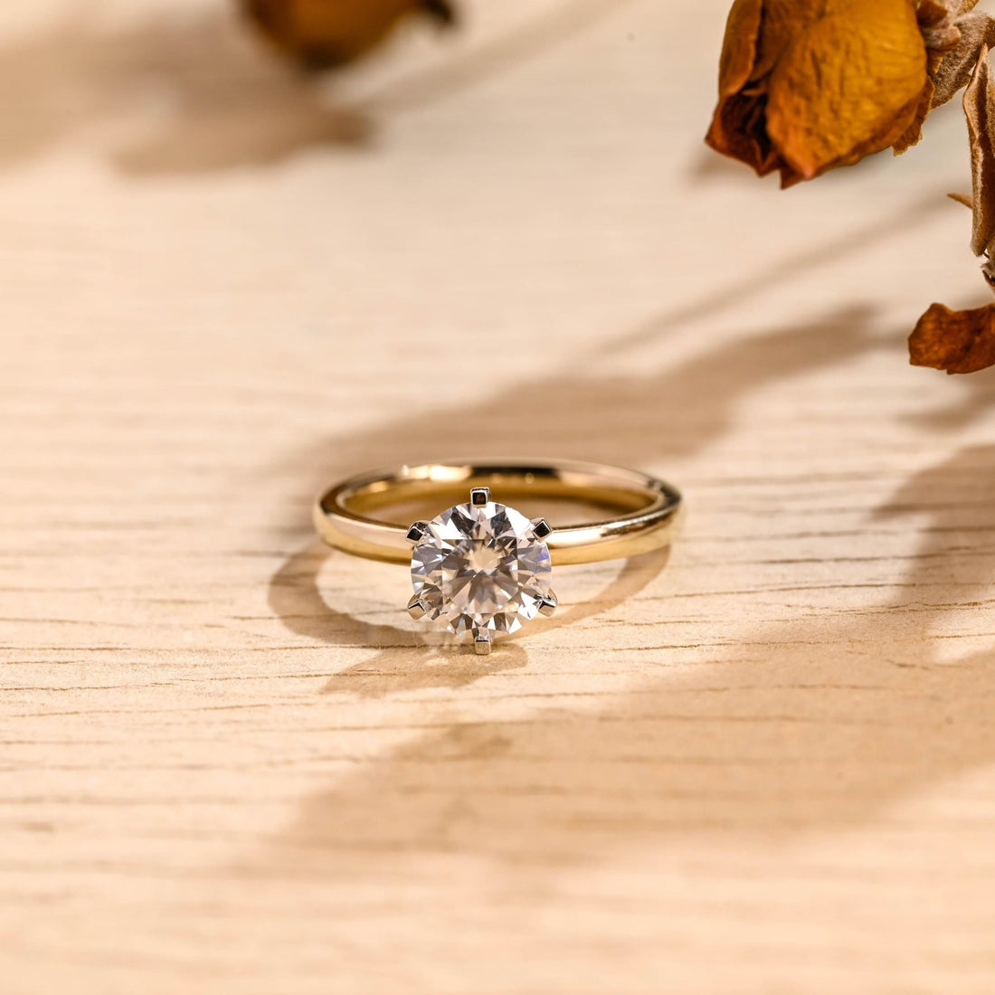 Round moissanite classic solitaire engagement ring in six slim claws on a plain polished yellow gold band