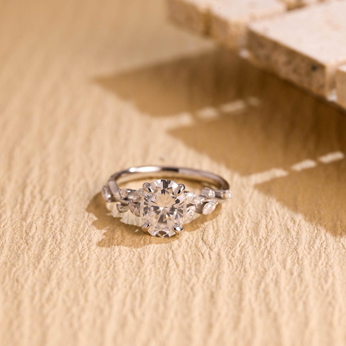 Oval moissanite nature inspired engagement ring with four claws and marquise leaves and small round buds along a twig style white gold band