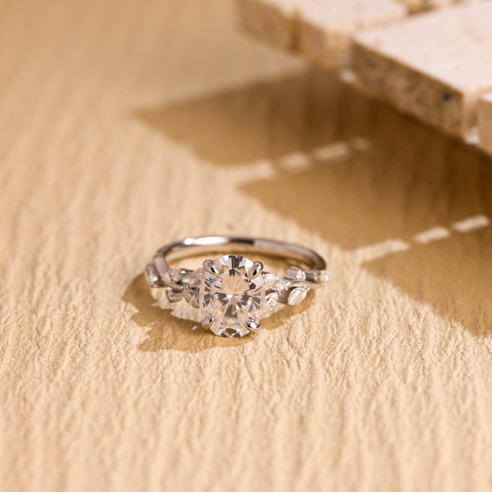 Oval moissanite nature inspired engagement ring with four claws and marquise leaves and small round buds along a twig style white gold band