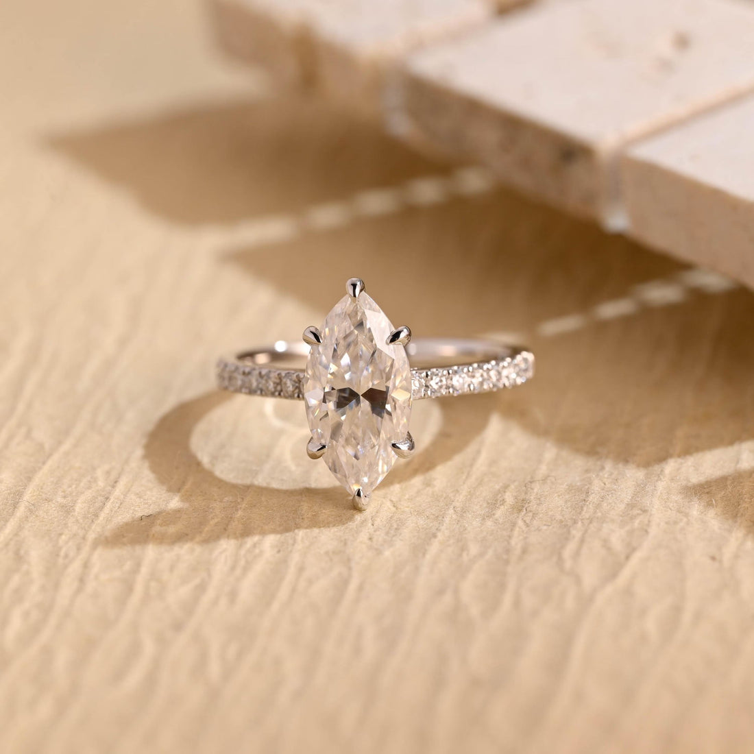 Elongated marquise cut moissanite six claw solitaire engagement ring with pave set shoulders on a white gold band