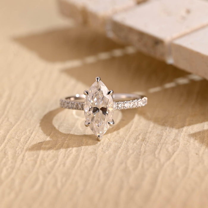 Elongated marquise cut moissanite six claw solitaire engagement ring with pave set shoulders on a white gold band