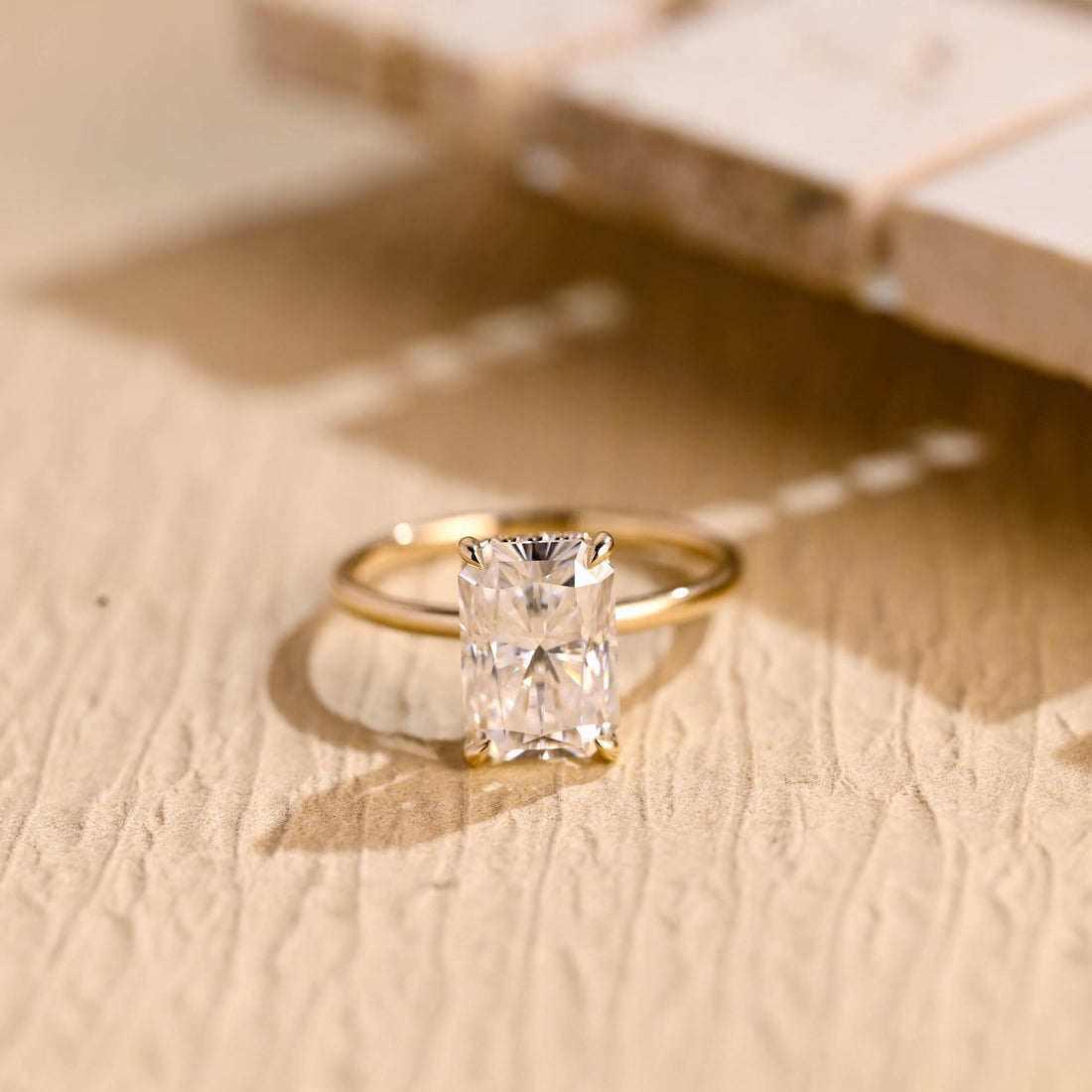 Large radiant cut moissanite hidden halo engagement ring with four claws on a slim polished yellow gold band
