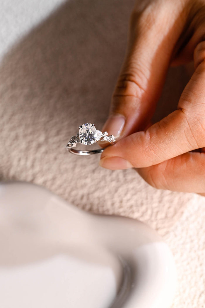 Oval moissanite nature inspired engagement ring with four claws and marquise leaves and small round buds along a twig style white gold band, view 2