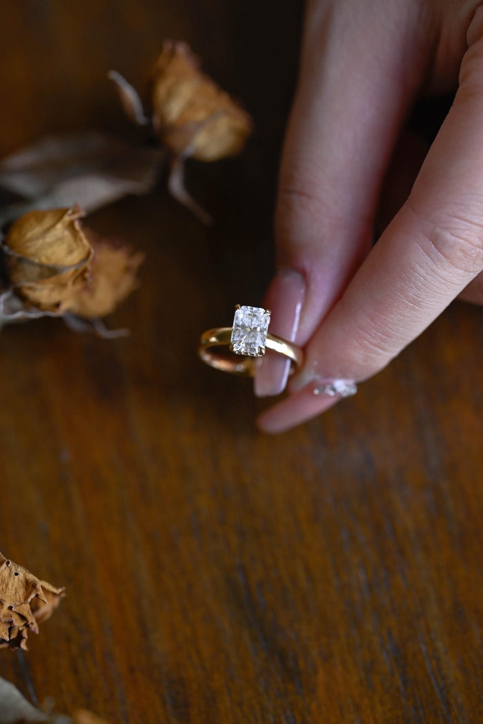 Radiant cut moissanite hidden halo engagement ring with four double claws on a polished yellow gold band, view 2