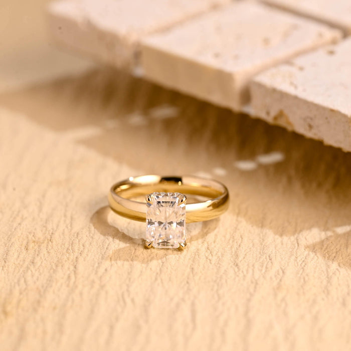 Radiant cut moissanite hidden halo engagement ring with four double claws on a polished yellow gold band