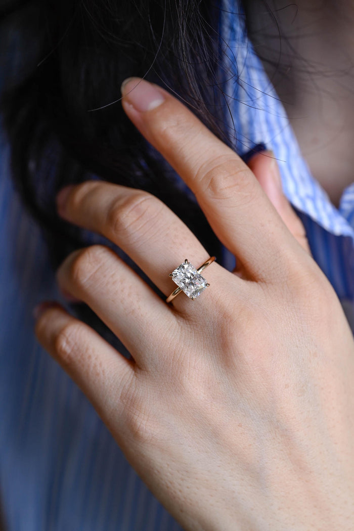 Large radiant cut moissanite hidden halo engagement ring with four claws on a slim polished yellow gold band, view 2
