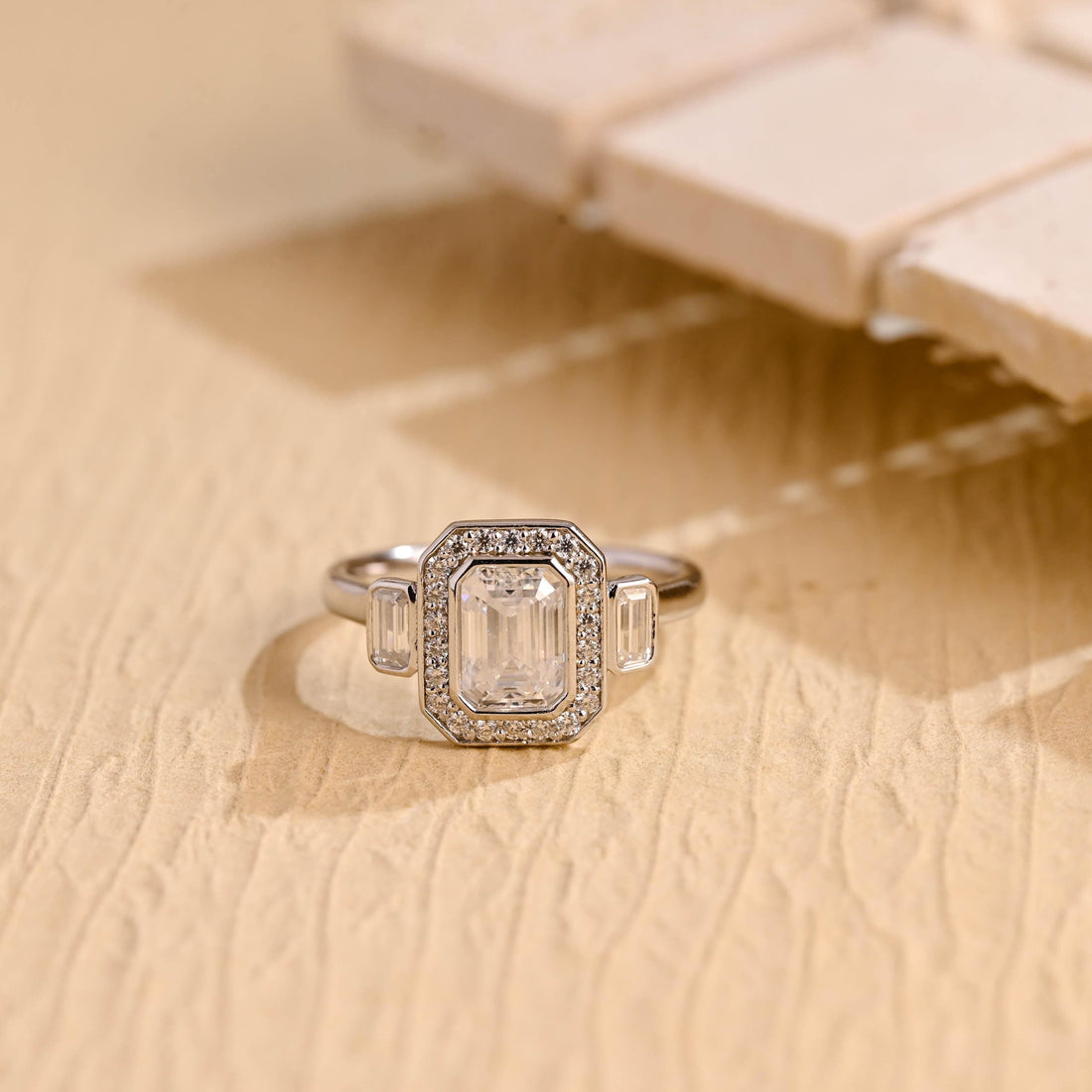 Emerald cut moissanite halo engagement ring with a baguette on each side in a white gold octagon setting