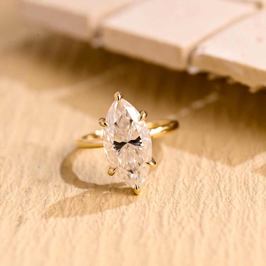 Large marquise cut moissanite hidden halo engagement ring with six teardrop claws on a slim yellow gold band