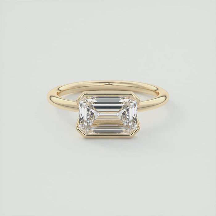 Emerald cut moissanite east west half bezel engagement ring in yellow gold
