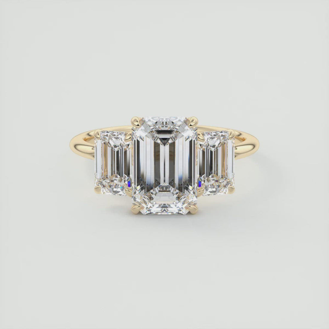 Emerald cut moissanite three stone engagement ring in yellow gold