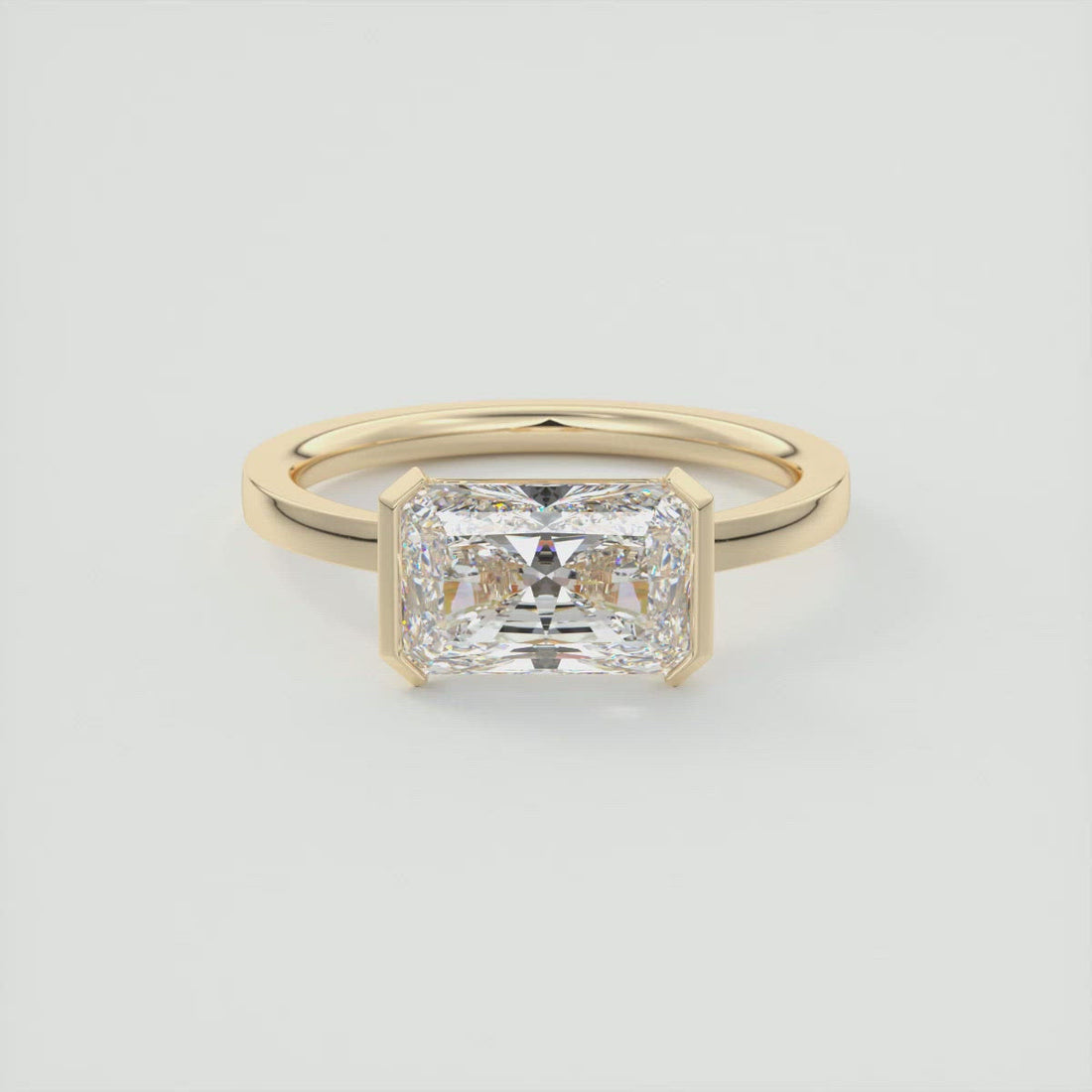 Radiant cut moissanite east west half bezel solitaire ring in yellow gold