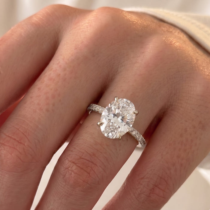 Kourtney Kardashian inspired elongated oval moissanite ring with hidden halo and pavé band in yellow gold, worn on the hand