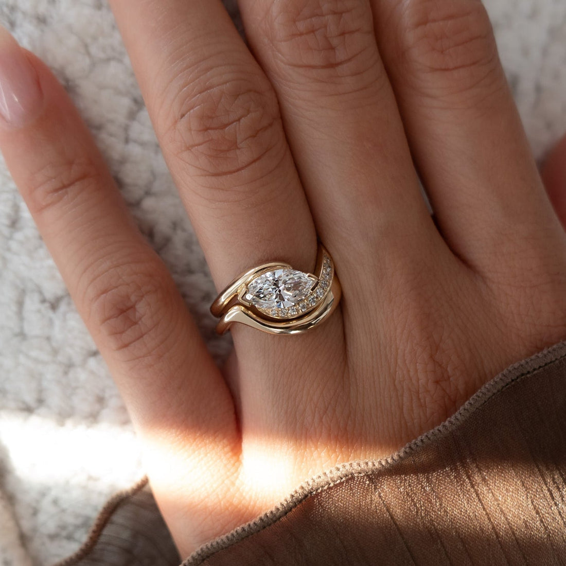 East-west marquise lab grown diamond half pave swirl ring with plain wave band in yellow gold on the hand