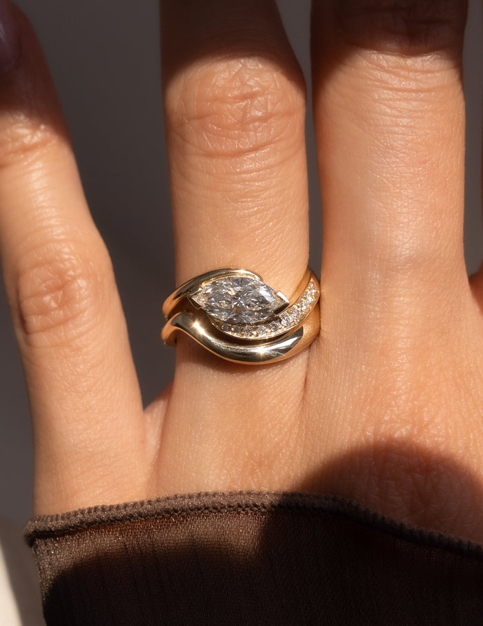 Close-up of east-west marquise lab grown diamond ring with stone-set bypass arm and plain gold wave band