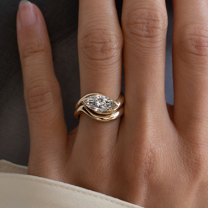 East-west marquise lab grown diamond swirl bridal set with plain wave band in yellow gold on the hand