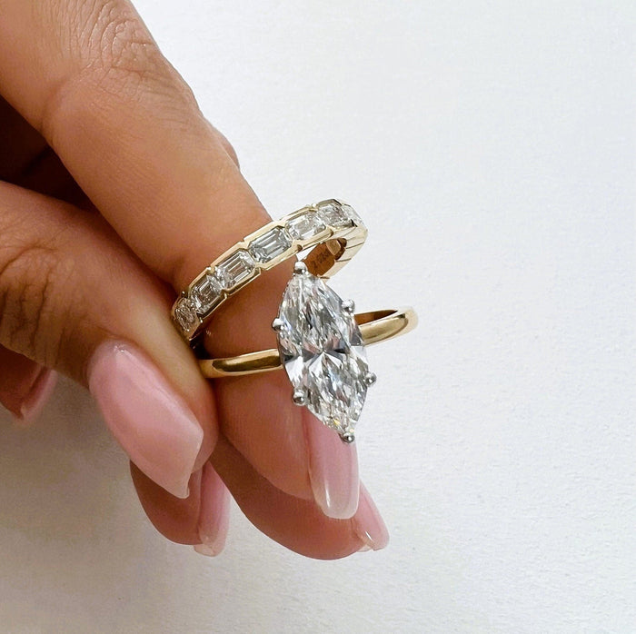 Marquise lab grown diamond solitaire and east-west emerald-cut band held in the fingers
