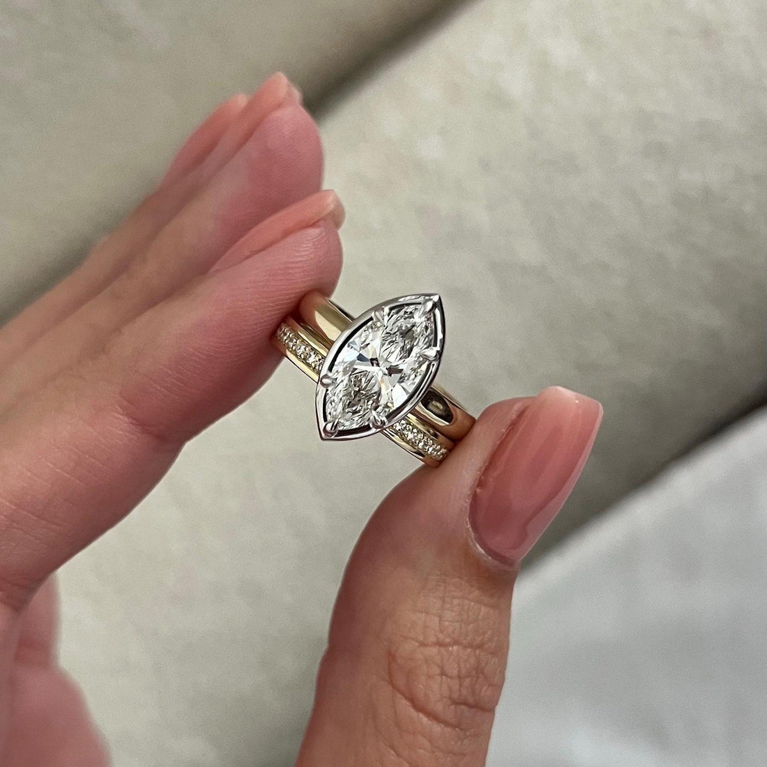 Marquise moissanite bezel solitaire and flat stone row band held in the fingers