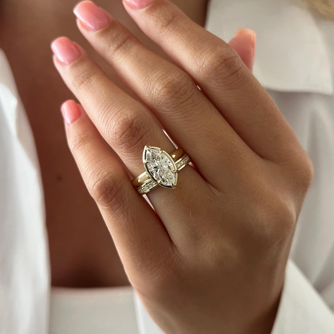 Marquise moissanite claw bezel bridal set with stone set band in yellow gold worn on the hand