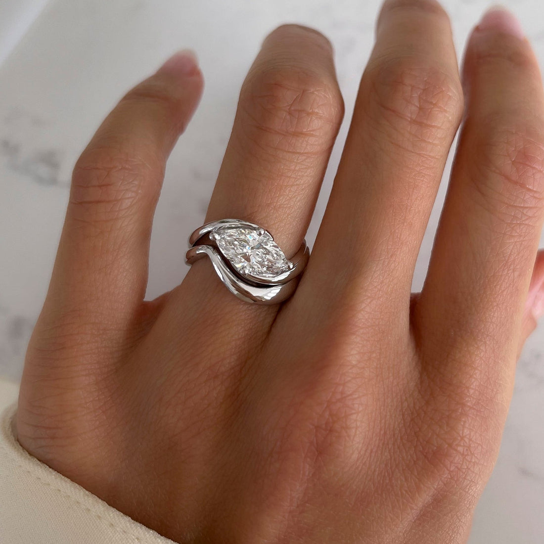 East-west marquise moissanite swirl bridal set with plain wave band in white gold on the hand