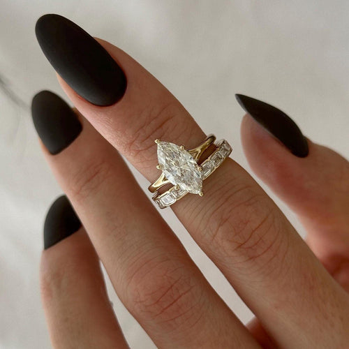 Marquise moissanite split shank bridal set with emerald-cut stone band in yellow gold on the hand