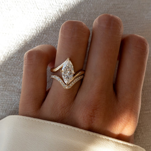 Marquise moissanite swirl bypass bridal set with pave V band in yellow gold on the hand
