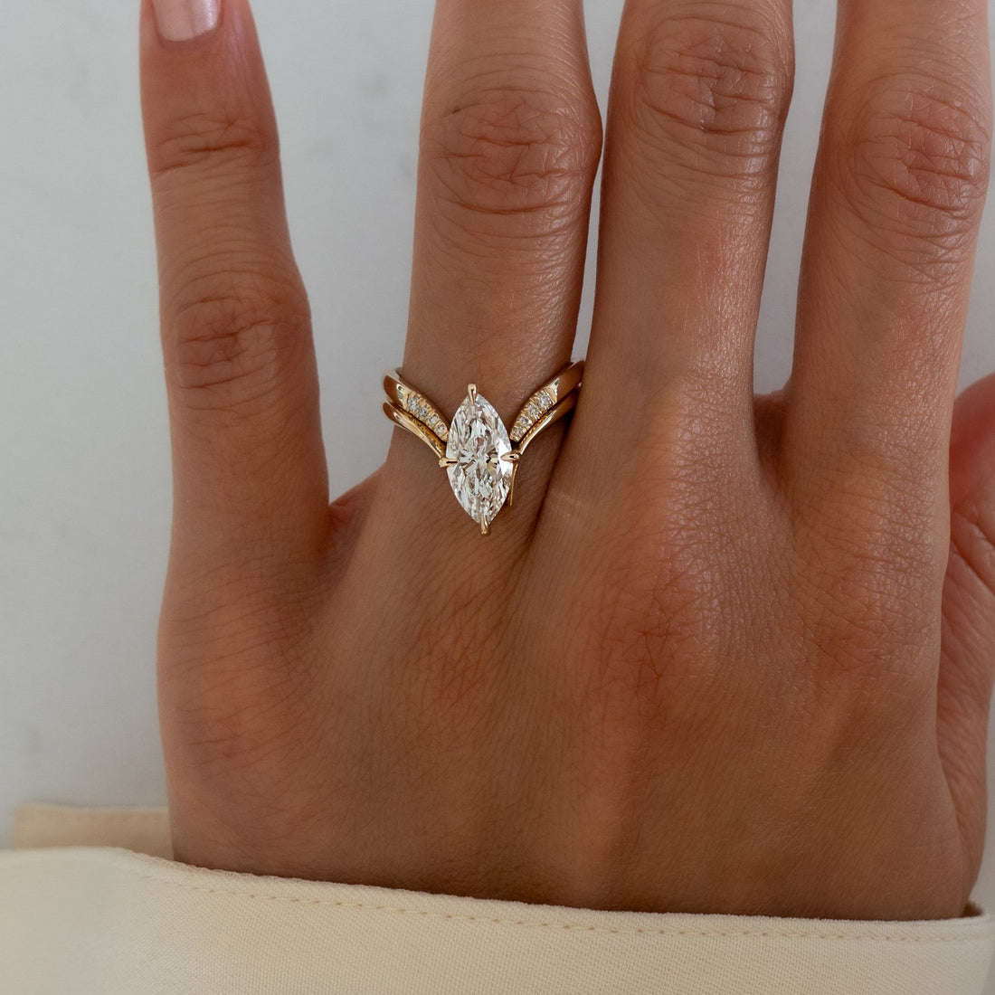 Marquise moissanite V shank bridal set with pave-tipped chevron band in yellow gold on the hand