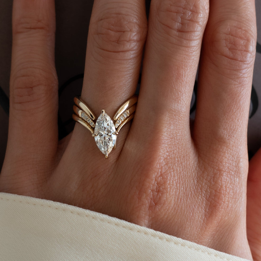 Marquise moissanite V shank ring stacked with plain and pave-tipped open chevron bands in yellow gold