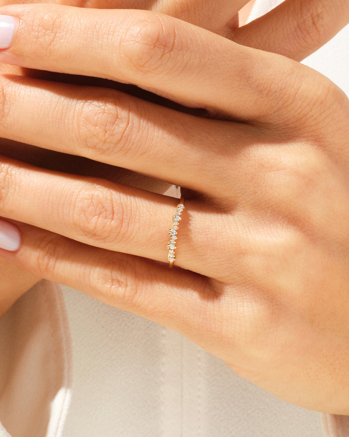 Dainty curved moissanite wedding band worn on the ring finger