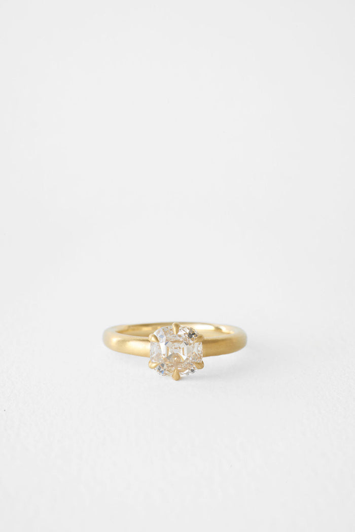 Antique cushion moissanite solitaire engagement ring on a brushed yellow gold band