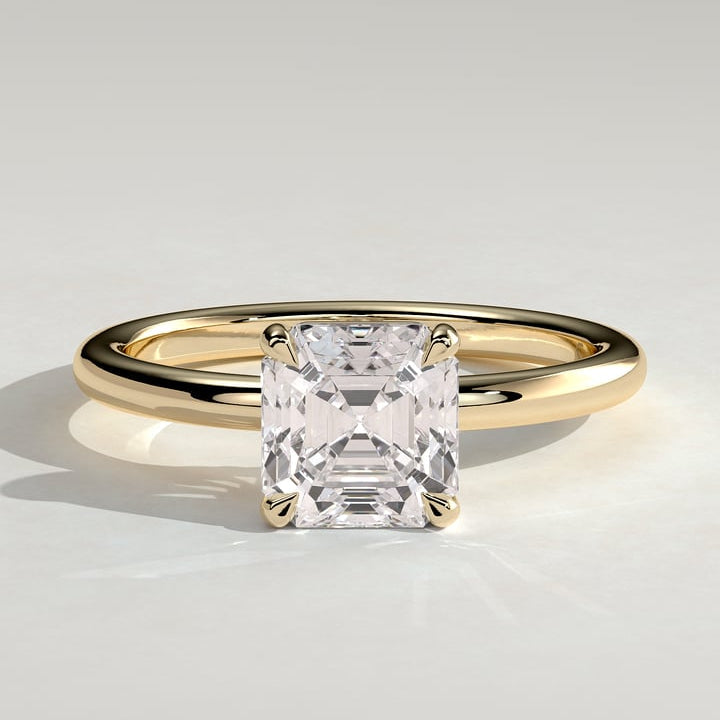 Asscher cut moissanite four claw solitaire engagement ring on a plain yellow gold band
