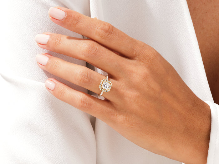 Asscher moissanite square halo ring with pave shoulders in yellow gold on the ring finger