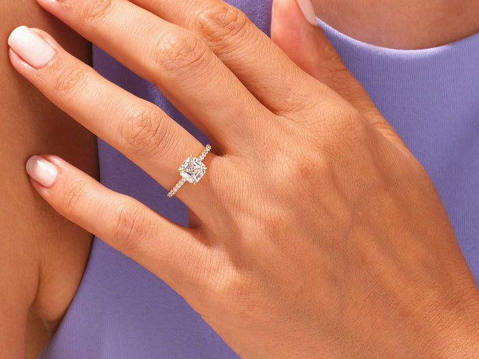 Large asscher moissanite pave ring worn on the hand against a lilac top