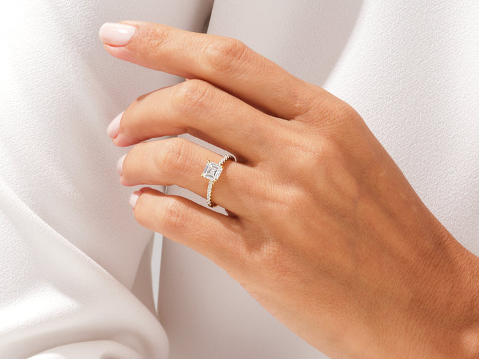 Asscher cut lab grown diamond pave band ring worn on the hand against a white sleeve