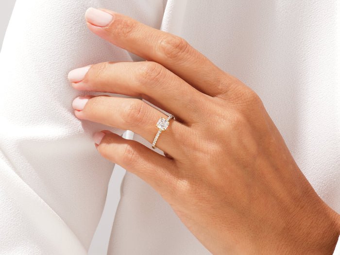 Asscher lab grown diamond half pave ring worn on a hand gathering white fabric