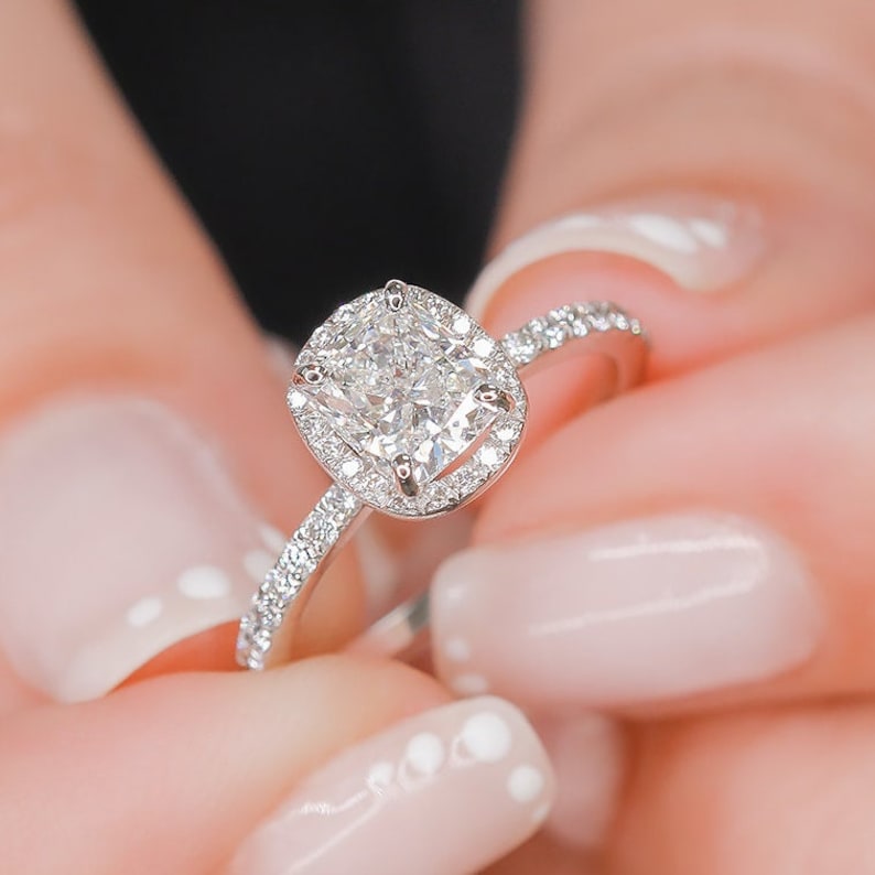 Cushion cut moissanite close fitted halo engagement ring on a fine pave band in white gold